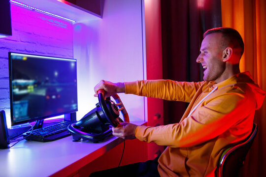 Male gamer playing racing games on the computer. He uses the steering wheel. Emotional game
