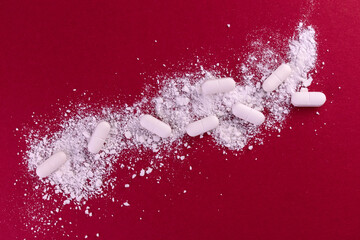 Medical background from crushed pills on a red background
