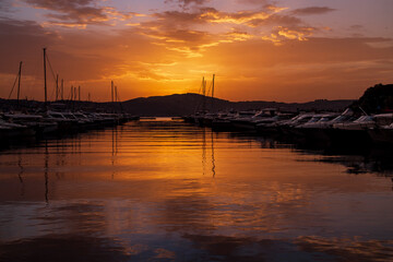 Sunrise in the seaside. Reflection of boats, walking people, fishermen