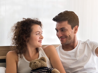 Happy newly wed couple spending quality time together in the bedroom. Caucasian couple looking at each other with love.