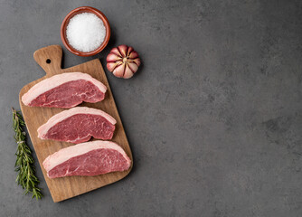 Sliced raw picanha or rump meat over wooden board with seasonings and copy space