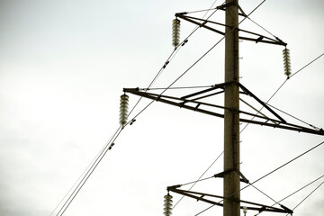 Reinforced concrete electric support. Electric wires. Gray urban background. Mainly cloudy.