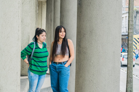 two beautiful latina women (friends), one Caucasian and the other brown-skinned, walking down the street while observing and criticizing other people. concept of gossip