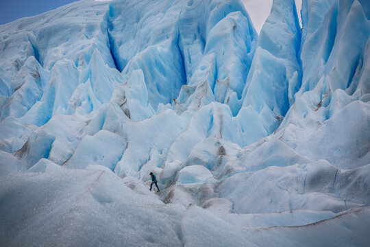 Im Herzen des Gletschers, ein Eiskletterer erscheint vor den riesigen blauen Eiszacken und Eistürmen des Perito Moreno Gletschers winzig und verloren