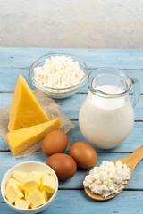 dairy products, cheese, butter, cottage cheese, eggs, milk on the table with white background, space for text, vertical photo