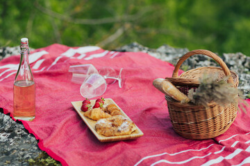 Picnic set with strawberries, croissants, baguette, wine, wicker basket for picnic with summer...
