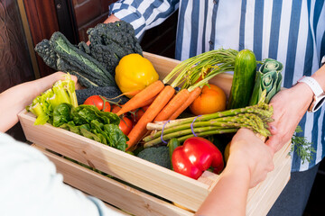 Home food delivery. Close up woman taking wooden box with fresh vegetables and fruits. Local farmer healthy food. New Start of a healthy life, weight loss concept. Online food order. Recipe box.