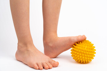 yellow needle ball for massage and physical therapy on a white background with a child's foot, the concept of prevention and treatment of foot valgus