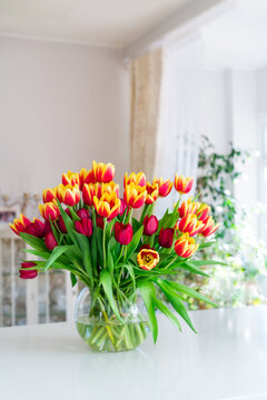 Huge spring colorful bouquet of tulips in vase on white table with classic interior design background. Gift for holiday, birthday, 8 March, Mother's Day, Valentine's day, Women's Day. Vertical card.
