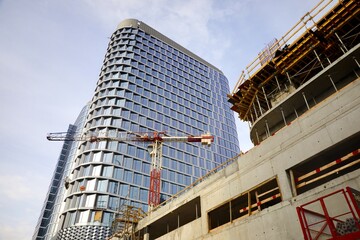 
Budowa biurowca apartamentowca z żurawiem budowlanym na tle błękitnego nieba