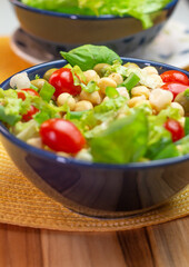  chickpeas with leaves, olives and tomatoes in two bowls on the table
