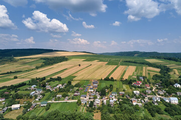 Fototapeta na wymiar Aerial landscape view of green cultivated agricultural fields with growing crops and distant village houses