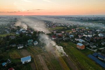 Aerial view of agricultural waste bonfires from dry grass and straw stubble burning with thick smoke polluting air during dry season on farmlands causing global warming and carcinogen fumes