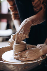 The potter works in the workshop. Potter makes a jug on a potter's wheel