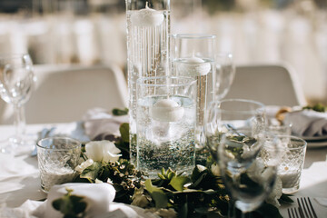 Elegant decorations on the wedding table with candles, vases and eucalyptus branches