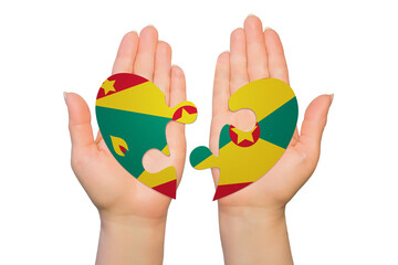 Woman hands are holding two parts of puzzle heart. National concept on white background. Grenada