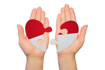 Woman hands are holding two parts of puzzle heart. National concept on white background. Indonesia