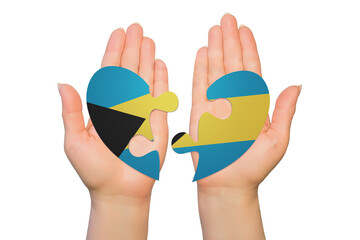 Woman hands are holding two parts of puzzle heart. National concept on white background. Bahamas