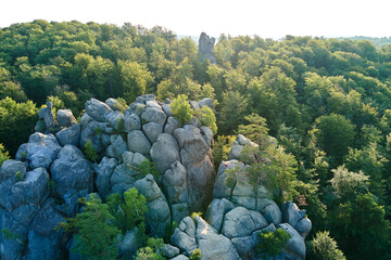 Aerial view of bright landscape with green forest trees and big rocky boulders between dense woods...