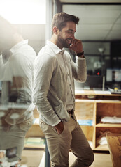 Just a few more minutes and then Im heading home. Shot of a handsome young businessman talking on a cellphone while working late in an office.