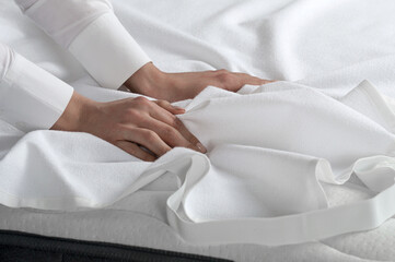 The girl changes the snow-white bed linen. Bedding