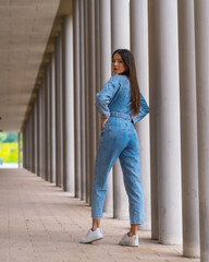 Fototapeta premium Young caucasian girl with a monkey cowboy next to a white columns. Enjoying the city on vacation, lifestyle of a young girl in a fashionable poster
