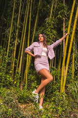 Young caucasian girl with a pink skirt in a bamboo forest. Enjoying the city on summer vacation in a tropical climate, lifestyle of a young girl in a trendy posing
