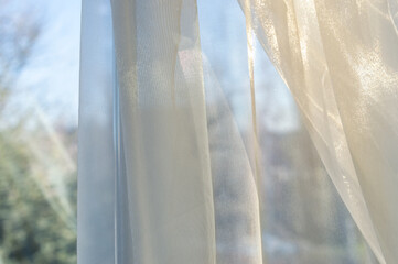 Weightless beautiful curtain on the window opening. Cream tulle on the window opening