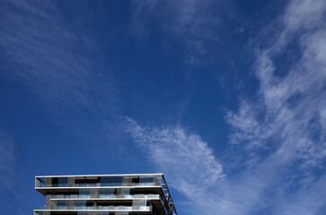 Nowoczesny apartamentowiec na tle błękitnego nieba z chmurami - obrazy, fototapety, plakaty