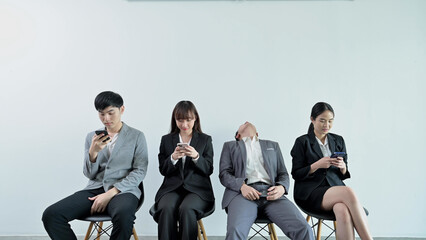 Tired businessman falling asleep while sitting waiting for a job interview and using mobile phone