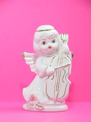 Ceramic figurine of an angel. White figurine of an angel with a cello.