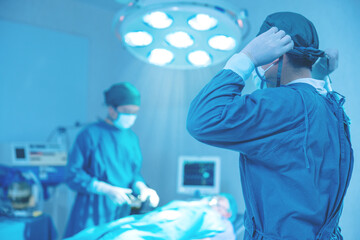 In the operating room of a hospital, a group of surgeons are performing surgery. In the operating...