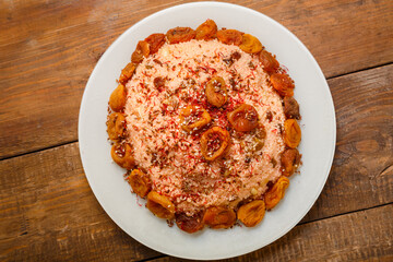 Masfouf from couscous on almond milk with dried fruits and nuts in a plate on a wooden table.