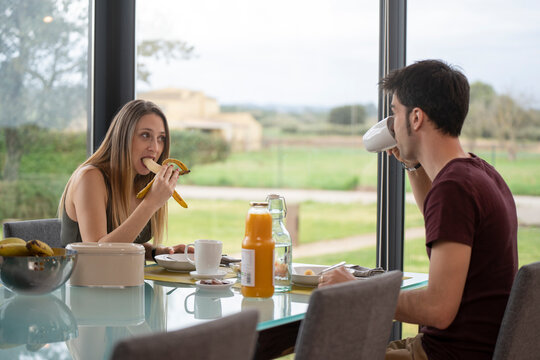 Young couple having breakfast in the living room at home near the garden