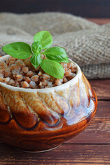Delicious buckwheat in a pot on a wooden background.
