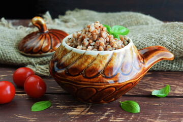 Delicious buckwheat in a pot on a wooden background.