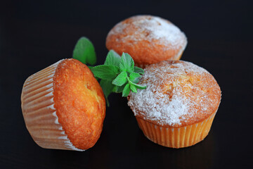 Delicious cupcakes and a sprig of greenery on a black background.