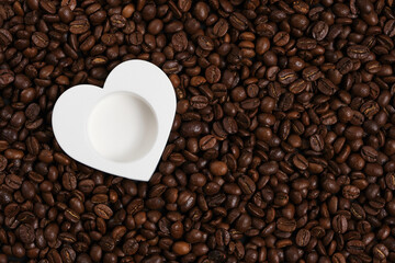 White heart on the background of roasted coffee beans.