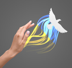 Female hand and paper dove on grey background. Stop the war in Ukraine