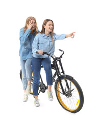 Portrait of happy young sisters with bicycle isolated on white