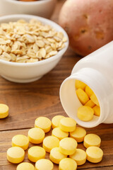 Bottle with pills and healthy products on wooden background