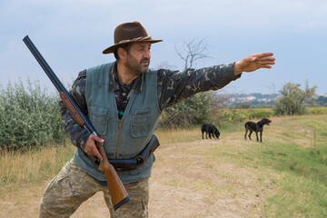 Hunter man in camouflage with a gun during the hunt in search of wild birds or game. Autumn hunting...