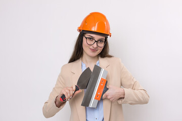 Girl engineer in an orange construction helmet with plastering painting tools in her hands on a white background.