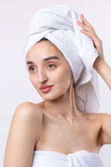 Beautiful girl with thick eyebrows and perfect skin at white background, towel on head, beauty photo.