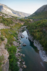 The purest water of the turquoise color of the river Moraca flowing among the canyon. A picturesque canyon among the high mountains covered with green forest in Montenegro.