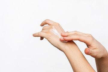 Close-up of woman's hands applying moisturizing cream on the skin isolated on a white background. Skin care concept