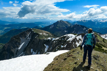 Woman hiking to the Frauenkogel (Dovska Baba) with scenic view on the Karawanks, Carinthia, Austria. Borders Austria, Slovenia, Italy. Triglav National Park. Mount Triglav and Mangart in the back. Awe