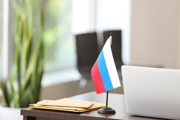 Russian flag, letters and laptop on table in office
