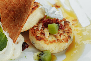 An ideal breakfast. Cottage cheese pancakes with caramel, almonds and cream sauce in a white plate. Ukrainian syrniki