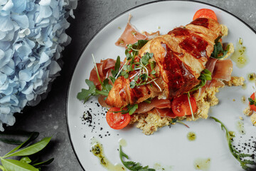 Delicious croissant sandwich with ham, cheese and scrambled eggs on plate served